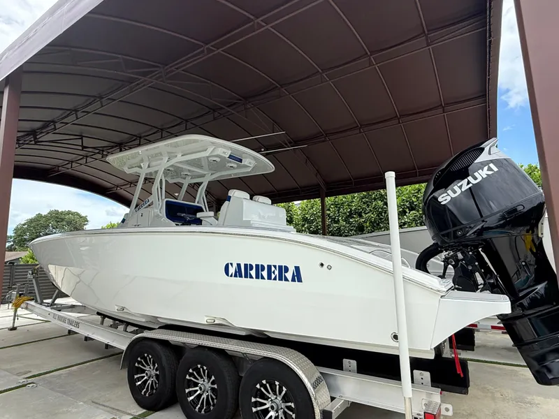 Slide: The Image of 2024 Carrera Powerboats 320CC Classic on trailer under canopy, featuring Suzuki outboard engine. - 0