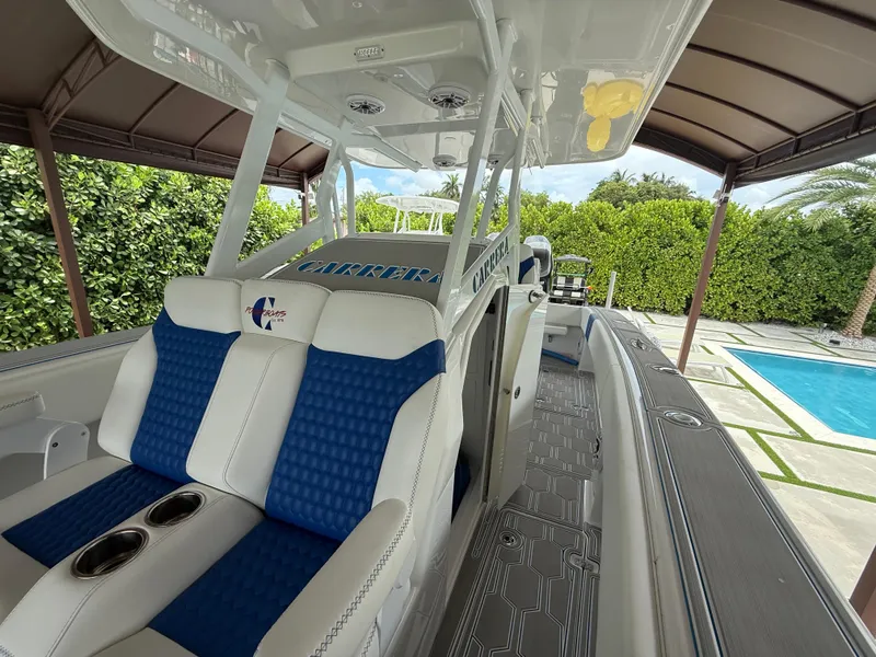 Slide: The Image of 2024 Carrera Powerboats 320CC Classic interior with blue and white seating, near a poolside. - 29