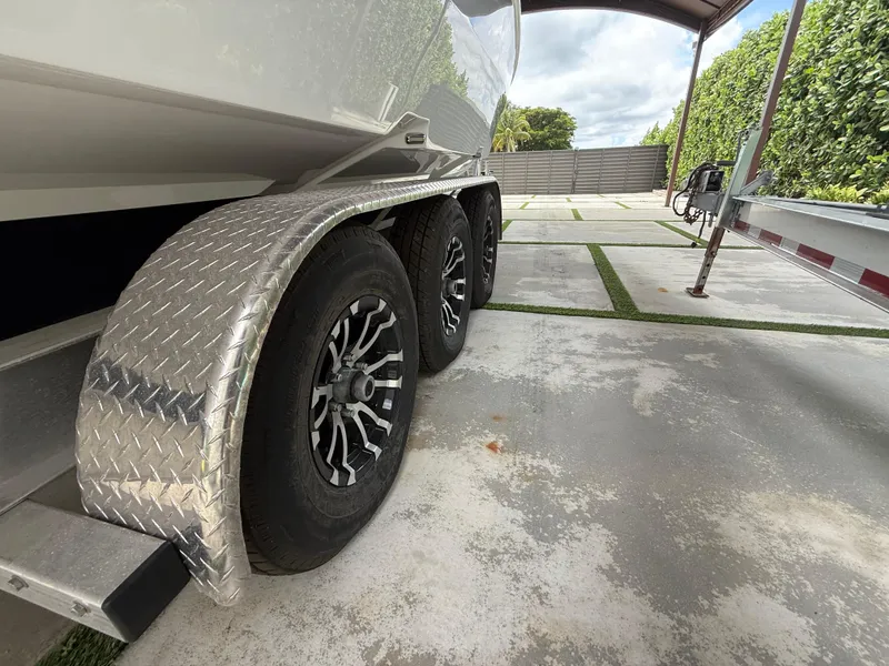 Slide: The Image of Trailer wheels of a 2024 Carrera Powerboats 320CC Classic on a concrete driveway. - 47
