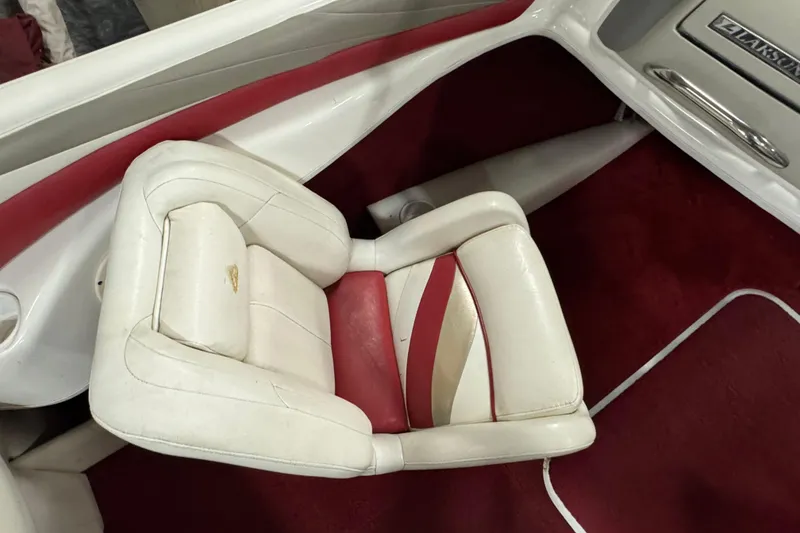 Slide: The Image of White and red interior of a 1998 Larson 195 boat, featuring a cushioned seat. - 14