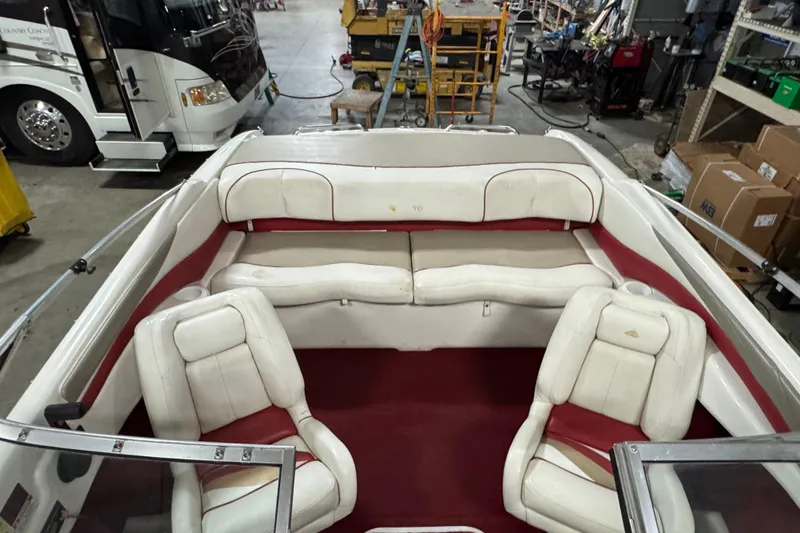 Slide: The Image of 1998 Larson 195 boat interior with white and red seating in a workshop setting. - 18