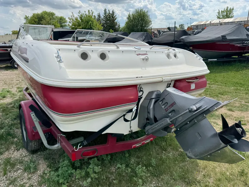 Slide: The Image of 1998 Larson 195 boat with visible front damage on a red trailer in a garage. - 3