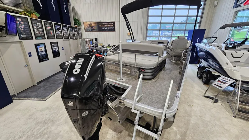Slide: The Image of 2020 Bennington L 25 Swingback pontoon boat displayed in showroom with outboard motor. - 5