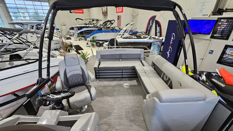 Slide: The Image of 2020 Bennington L 25 Swingback pontoon boat interior in showroom, featuring spacious seating and helm. - 8