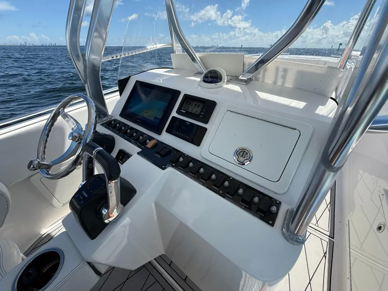 Slide: The Image of 2021 Avance 33 Cabriolet boat dashboard with steering wheel and navigation controls on open water. - 9