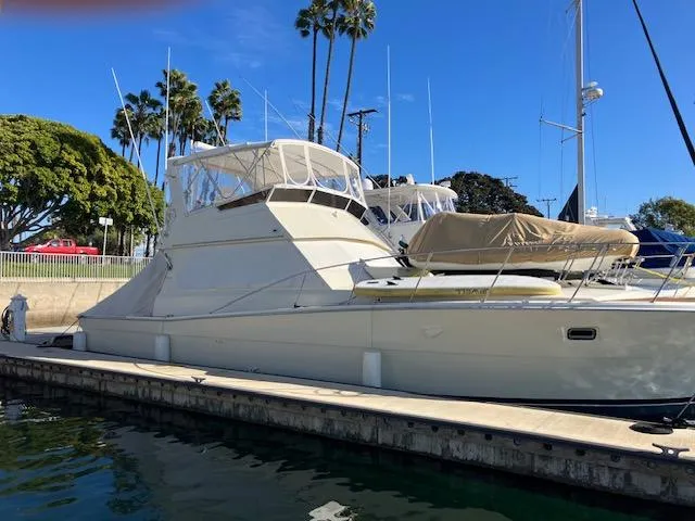 The Image of 1983 Viking Convertible yacht docked at marina, surrounded by palm trees and clear blue sky. - 0