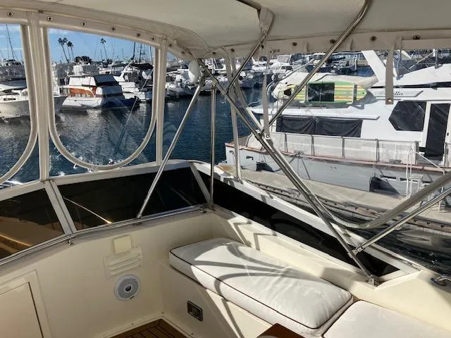Slide: The Image of 1983 Viking Convertible yacht interior with marina view, featuring white seating and metal framework. - 38