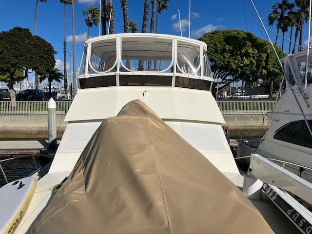 Slide: The Image of 1983 Viking Convertible boat docked, covered, with palm trees and blue sky in the background. - 47
