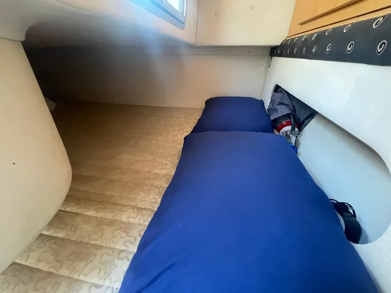 Slide: The Image of Interior cabin of a 2003 Larson 270 boat with blue cushions and storage space. - 14