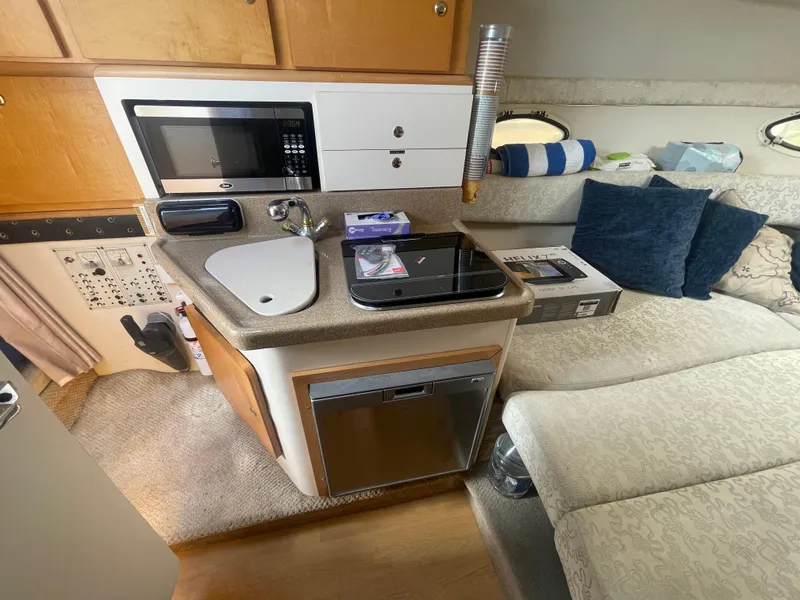 Slide: The Image of 2003 Larson 270 boat interior with kitchenette, microwave, sink, and seating area. - 15