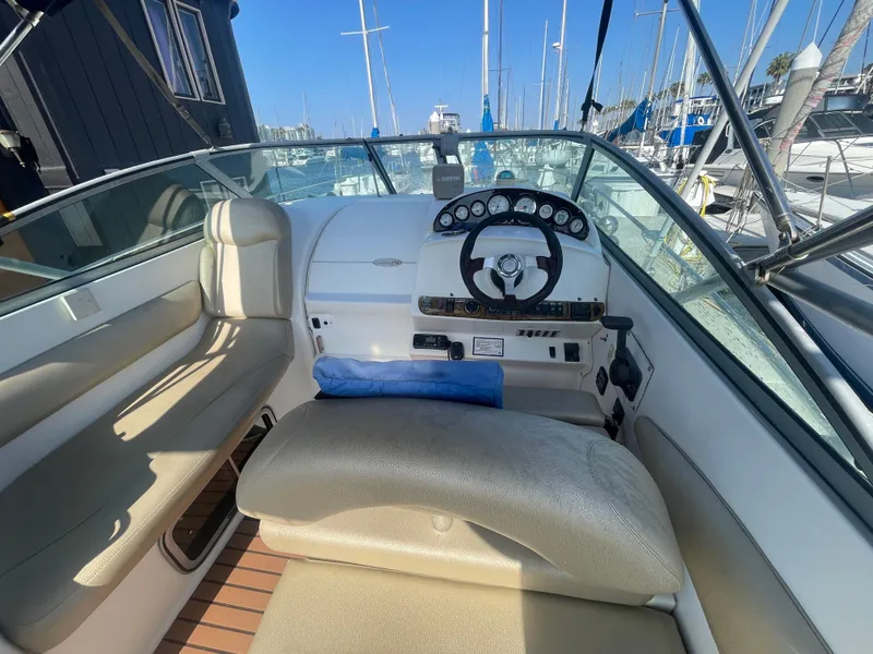 Slide: The Image of 2003 Larson 270 boat cockpit with steering wheel, beige seating, and marina view. - 5