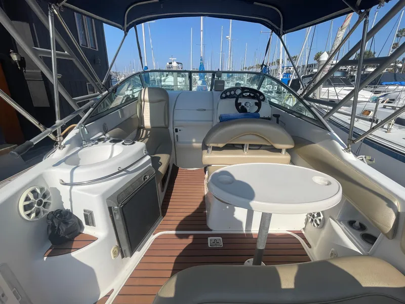Slide: The Image of Interior of a 2003 Larson 270 boat with seating and table, docked at a marina. - 8