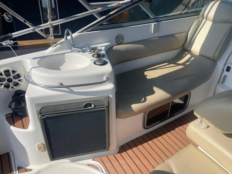 Slide: The Image of 2003 Larson 270 boat interior with seating, sink, and storage on teak flooring. - 9