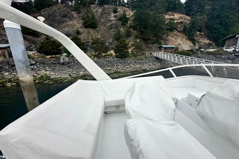Slide: The Image of 2000 Carver 374 Voyager yacht with covered seating, docked near a rocky shoreline. - 20