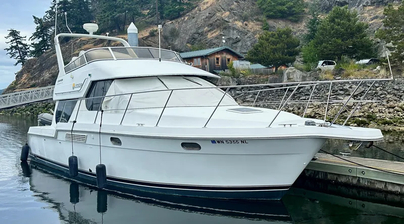 Slide: The Image of 2000 Carver 374 Voyager yacht docked by rocky shoreline with trees. - 2