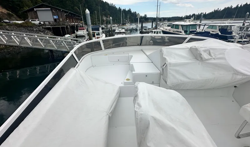 Slide: The Image of 2000 Carver 374 Voyager yacht deck with covered seating, docked in a scenic marina. - 21