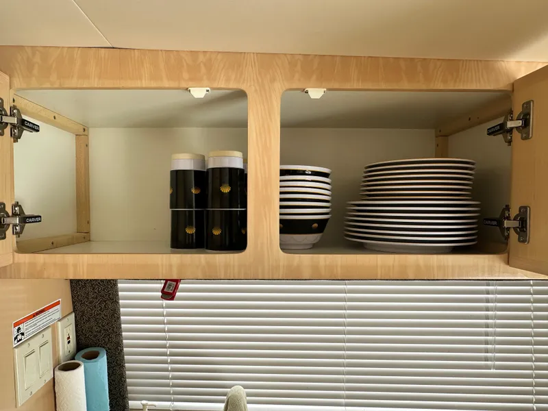 Slide: The Image of Open cabinet in Carver 374 Voyager, displaying neatly stacked dishes and cups. - 31