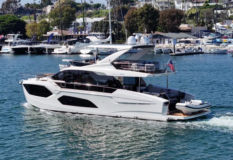 Slide: The Image of 2024 Absolute 60 Fly Co Ownership yacht cruising in a marina with other boats. - 2