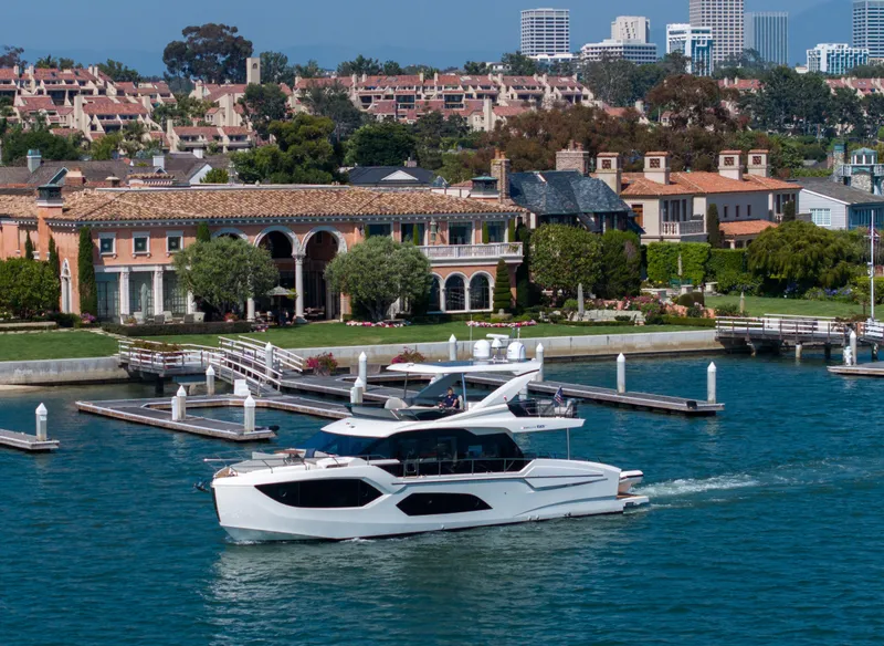 Slide: The Image of 2024 Absolute 60 Fly Co Ownership yacht cruising near luxury waterfront homes. - 3