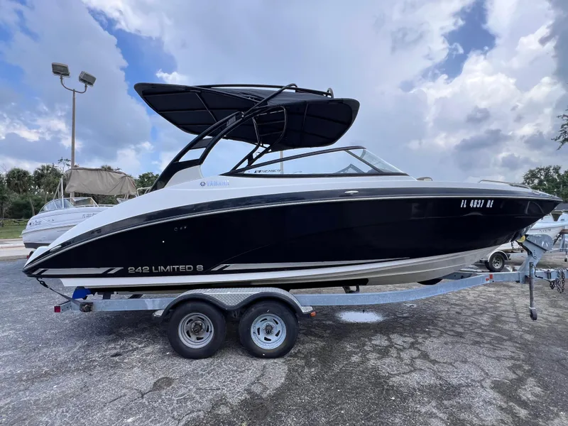 Slide: The Image of 2016 Yamaha Boats 242 Limited S E-Series on trailer, black exterior, parked outdoors. - 2