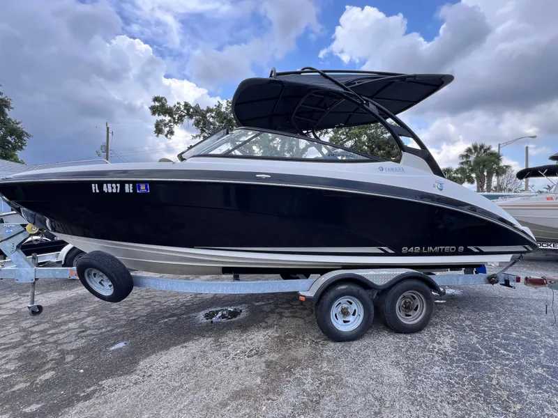 Slide: The Image of 2016 Yamaha Boats 242 Limited S E-Series on trailer, black hull, cloudy sky background. - 3