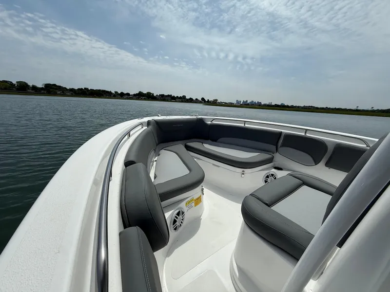 Slide: The Image of 2025 NauticStar 212 Legacy boat interior with cushioned seating on a calm lake. - 11
