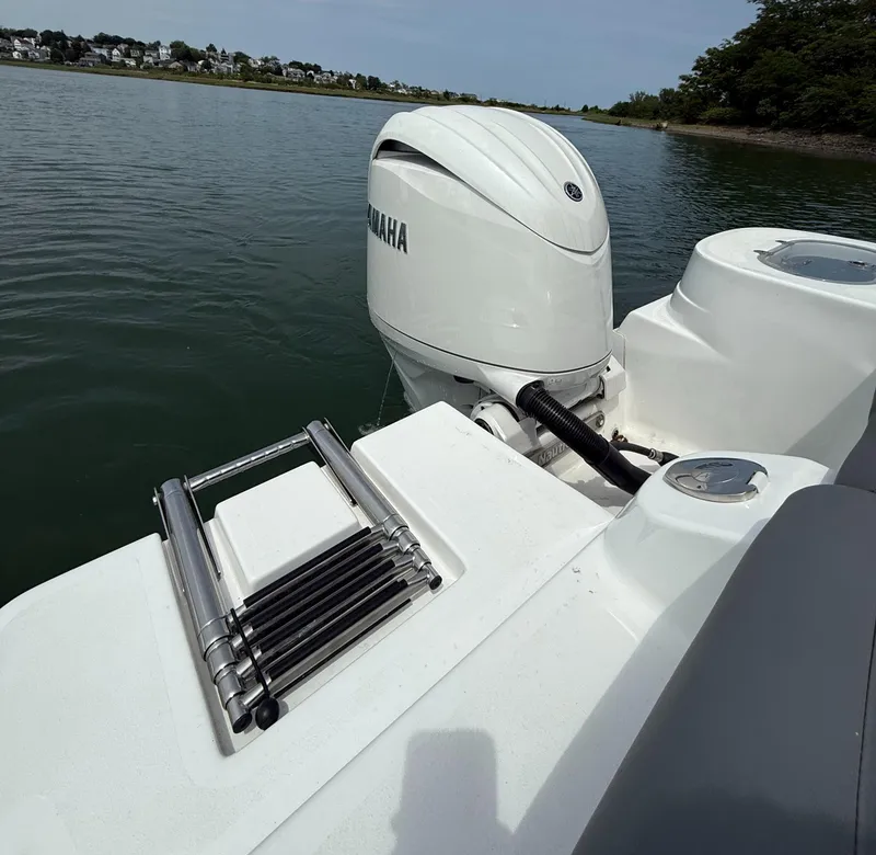 Slide: The Image of 2025 NauticStar 212 Legacy boat with Yamaha outboard motor and swim ladder on calm water. - 13