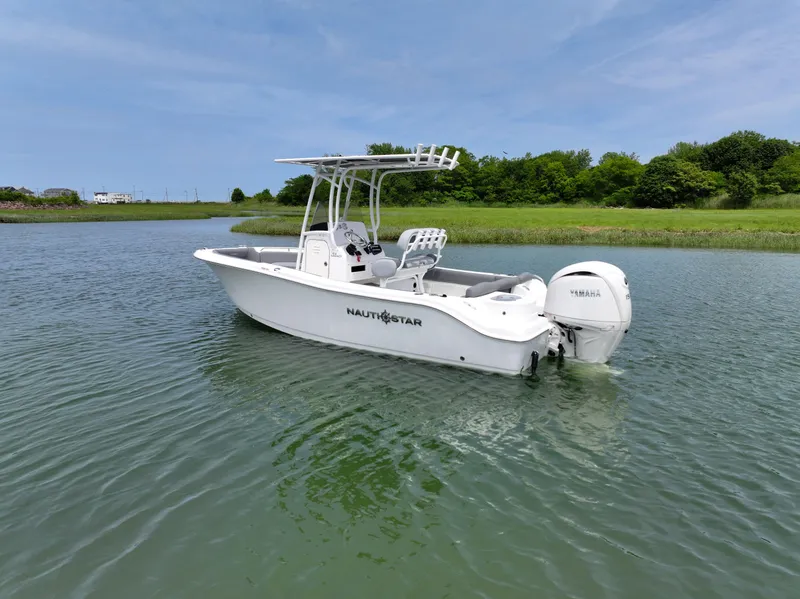 Slide: The Image of 2025 NauticStar 212 Legacy boat on calm water, featuring sleek design and Yamaha outboard motor. - 2