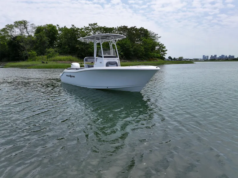 Slide: The Image of 2025 NauticStar 212 Legacy boat on calm water near lush shoreline. - 3