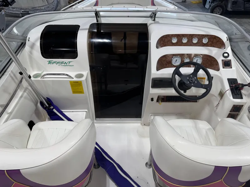 Slide: The Image of Cockpit of a 1997 Thompson Torrent 2900 boat with white seats and dashboard controls. - 6