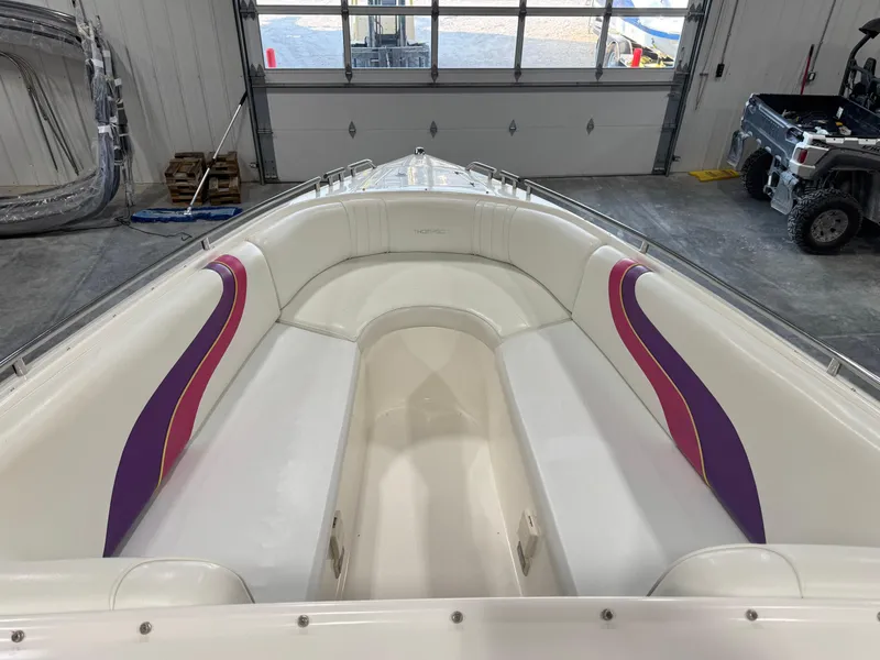 Slide: The Image of 1997 Thompson Torrent 2900 boat interior with white and purple seating in a garage. - 8