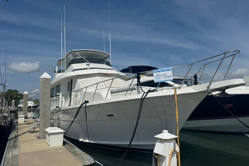 The Image of 1995 Hatteras 74 Cockpit Motor Yacht docked at marina under clear sky. - 0