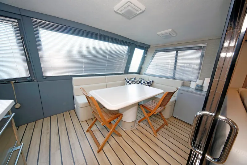 Slide: The Image of Interior of 1995 Hatteras 74 Cockpit Motor Yacht with dining area and wooden flooring. - 17