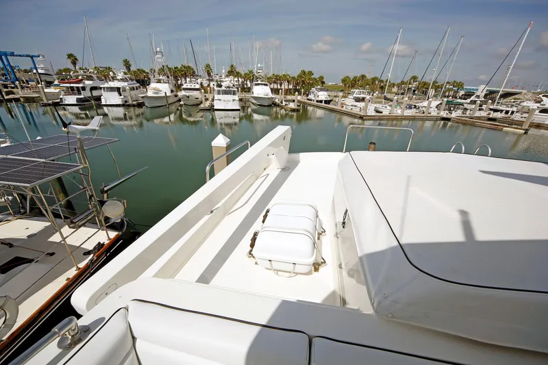 Slide: The Image of 1995 Hatteras 74 Cockpit Motor Yacht docked in a marina with other boats. - 68