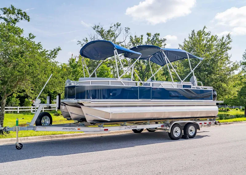 Slide: The Image of 2025 Tahoe SPORTS 85 REAR FISH pontoon boat on trailer, parked on a sunny street. - 1