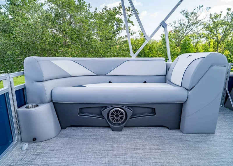 Slide: The Image of 2025 Tahoe SPORTS 85 REAR FISH boat seating with speaker, cup holder, and lush greenery background. - 8