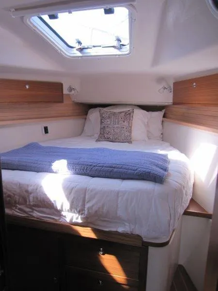 Slide: The Image of 2024 Catalina 385 yacht cabin with cozy bed, wooden accents, and skylight. - 16