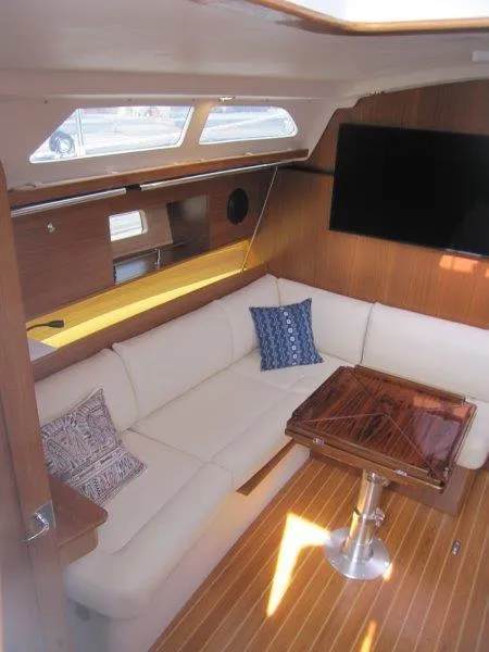 Slide: The Image of 2024 Catalina 385 yacht interior with white seating, wooden table, and large window. - 2