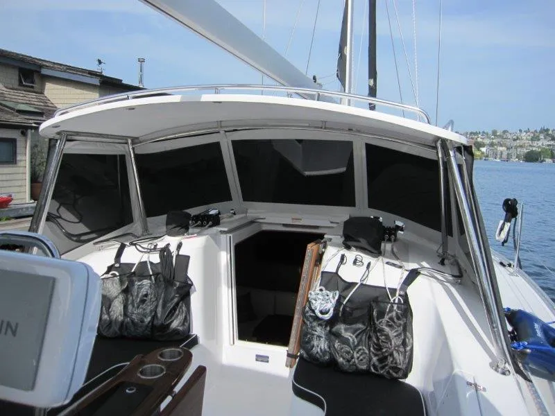 Slide: The Image of 2024 Catalina 385 sailboat cockpit with seating and storage bags, docked by waterfront homes. - 44