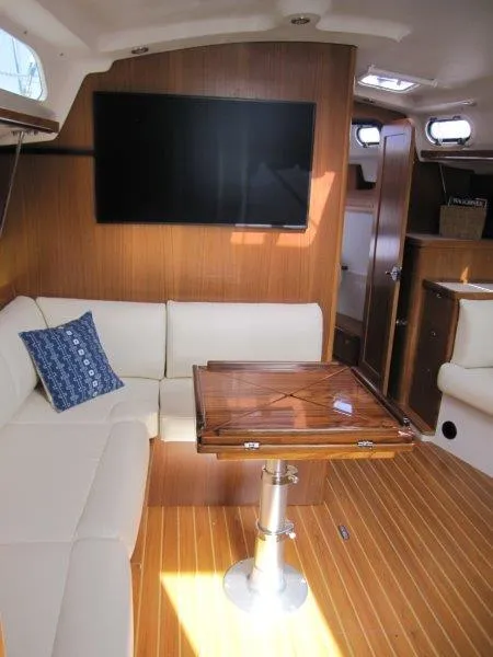 Slide: The Image of 2024 Catalina 385 yacht interior with modern seating, wooden table, and mounted TV. - 8