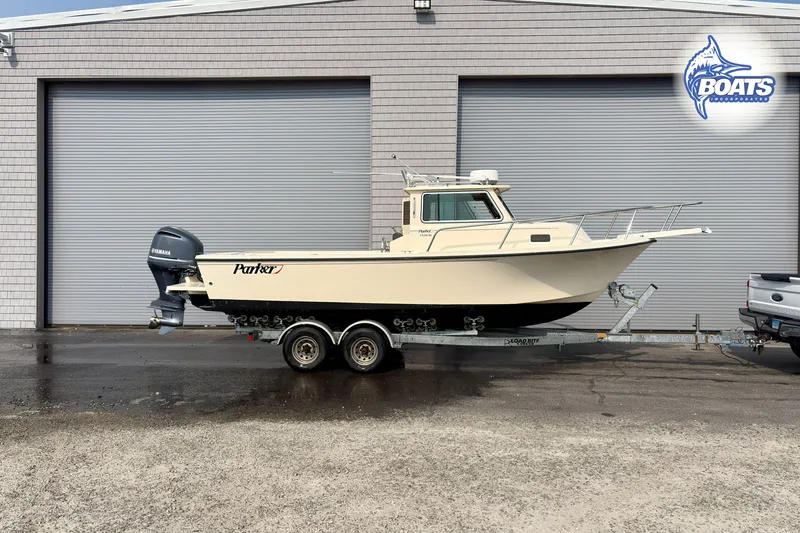 Slide: The Image of 2011 Parker Sport Cabin SL boat on trailer, parked outside a garage. - 0