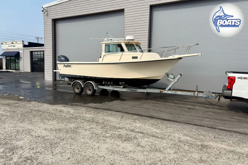 Slide: The Image of 2011 Parker Sport Cabin SL boat on trailer outside a garage. - 1