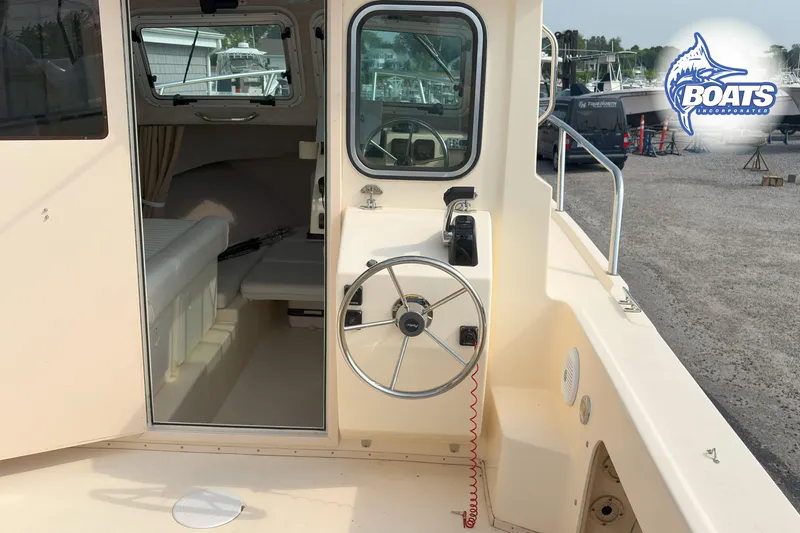 Slide: The Image of 2011 Parker Sport Cabin SL boat interior with steering wheel and cabin view. - 15