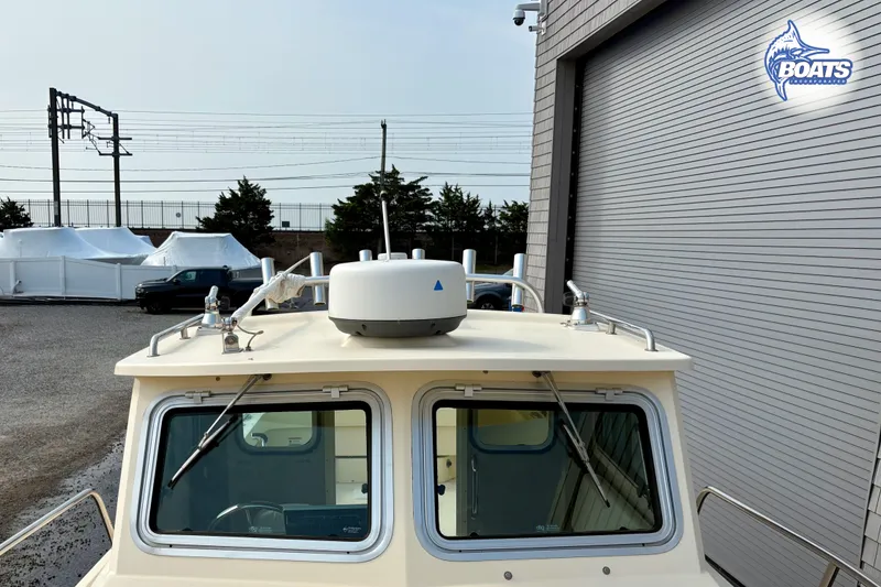 Slide: The Image of 2011 Parker Sport Cabin SL boat front view with radar, parked near a building. - 7