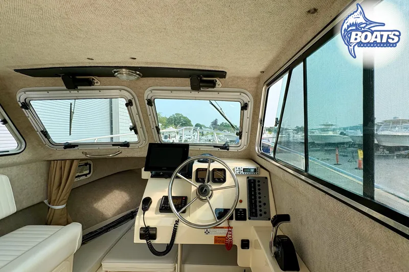 Slide: The Image of Interior view of 2011 Parker Sport Cabin SL boat, featuring steering wheel and control panel. - 8
