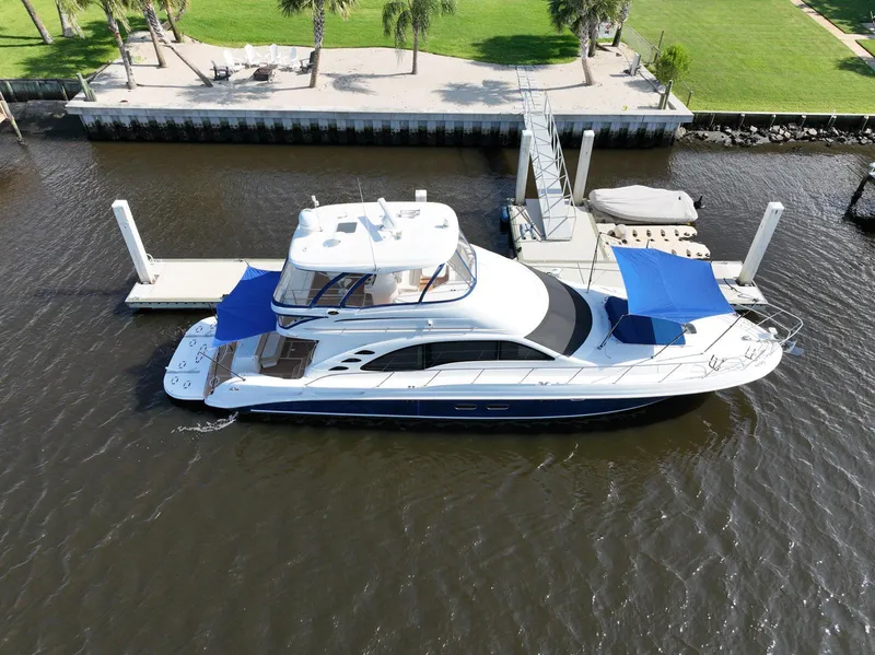 Slide: The Image of 2006 Sea Ray 580 Sedan Bridge yacht docked at marina with blue canopies. - 1
