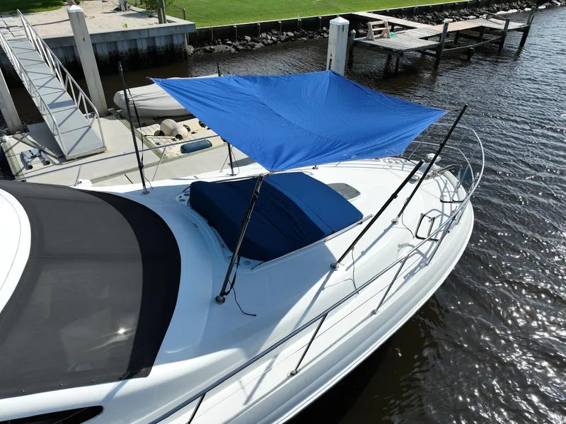 Slide: The Image of 2006 Sea Ray 580 Sedan Bridge with blue canopy docked by the water. - 10