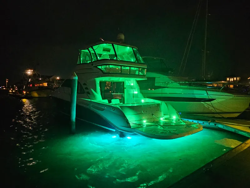 Slide: The Image of 2006 Sea Ray 580 Sedan Bridge yacht illuminated with green lights at night. - 12