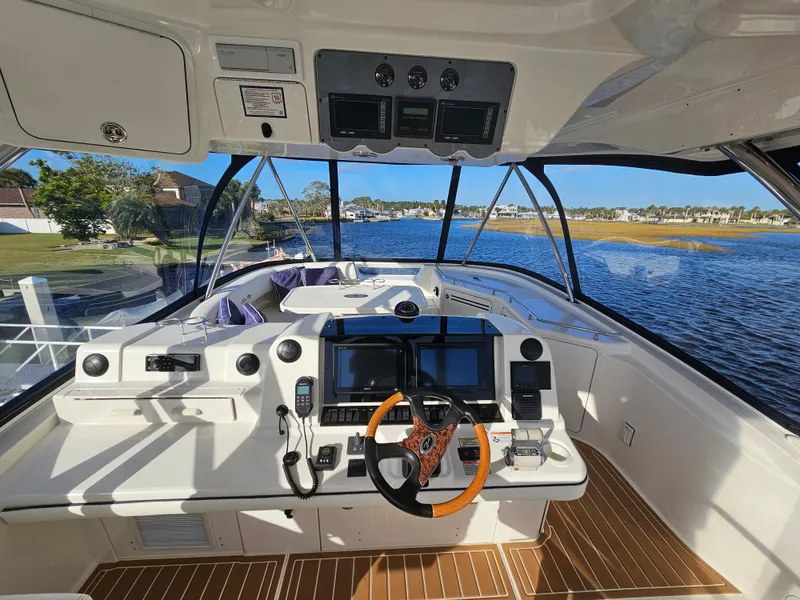 Slide: The Image of 2006 Sea Ray 580 Sedan Bridge helm with modern controls, overlooking serene waterfront. - 13