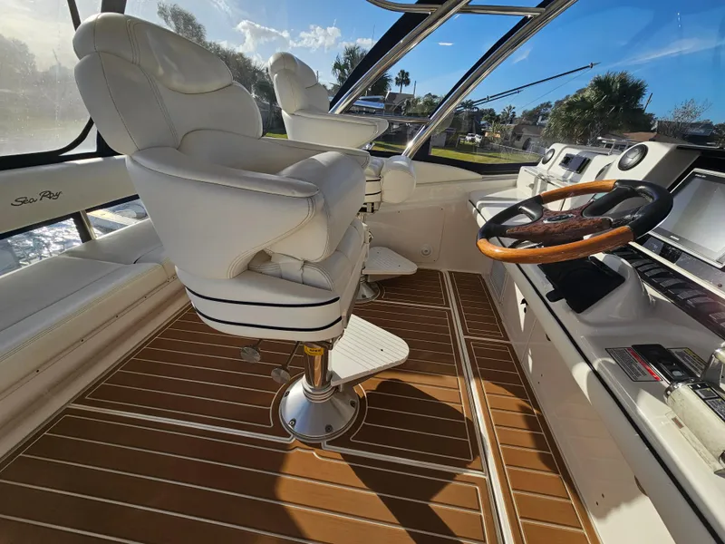 Slide: The Image of 2006 Sea Ray 580 Sedan Bridge helm with white captain chairs and wooden steering wheel. - 17